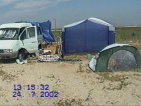 возведение лагеря: уже видна моя палатка и только что поставили навес - под ним пока пусто. Возле машины лежит куча барахла и детский бассейн